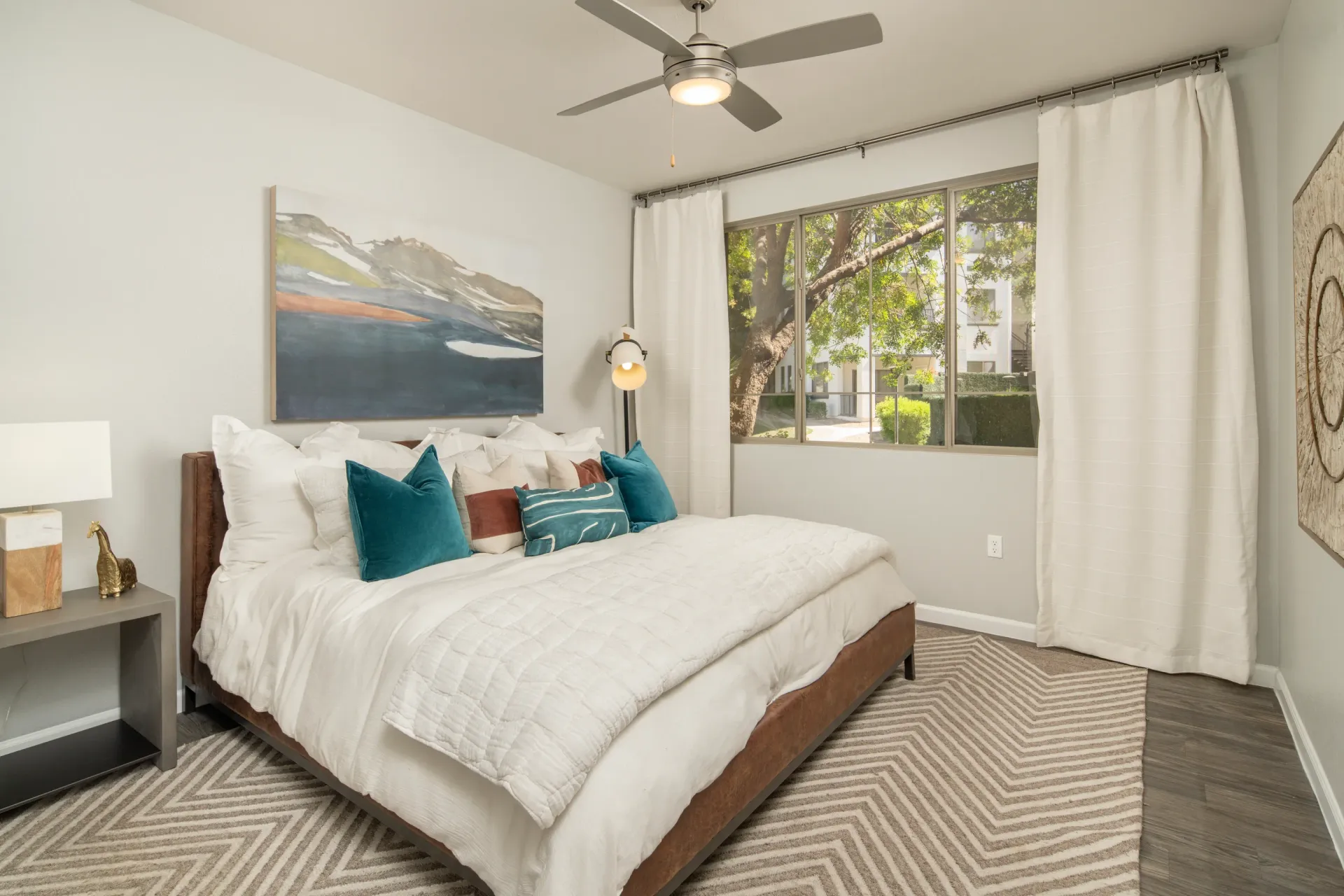 Bedroom with a large bed, ceiling fan, and window view.