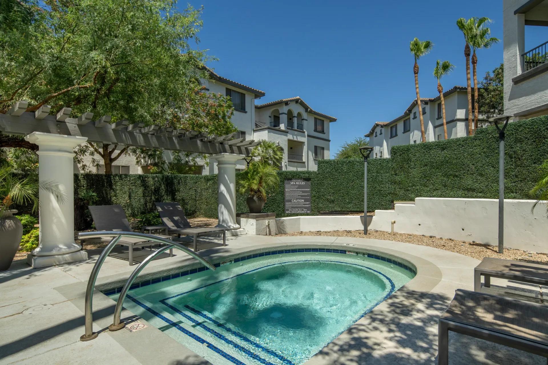 Outdoor spa with lounge chairs and surrounding apartment buildings.