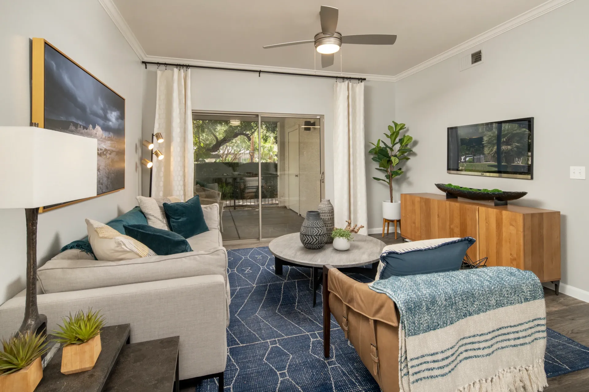 Living room with a sofa, coffee table, TV, and sliding glass doors leading to a patio.