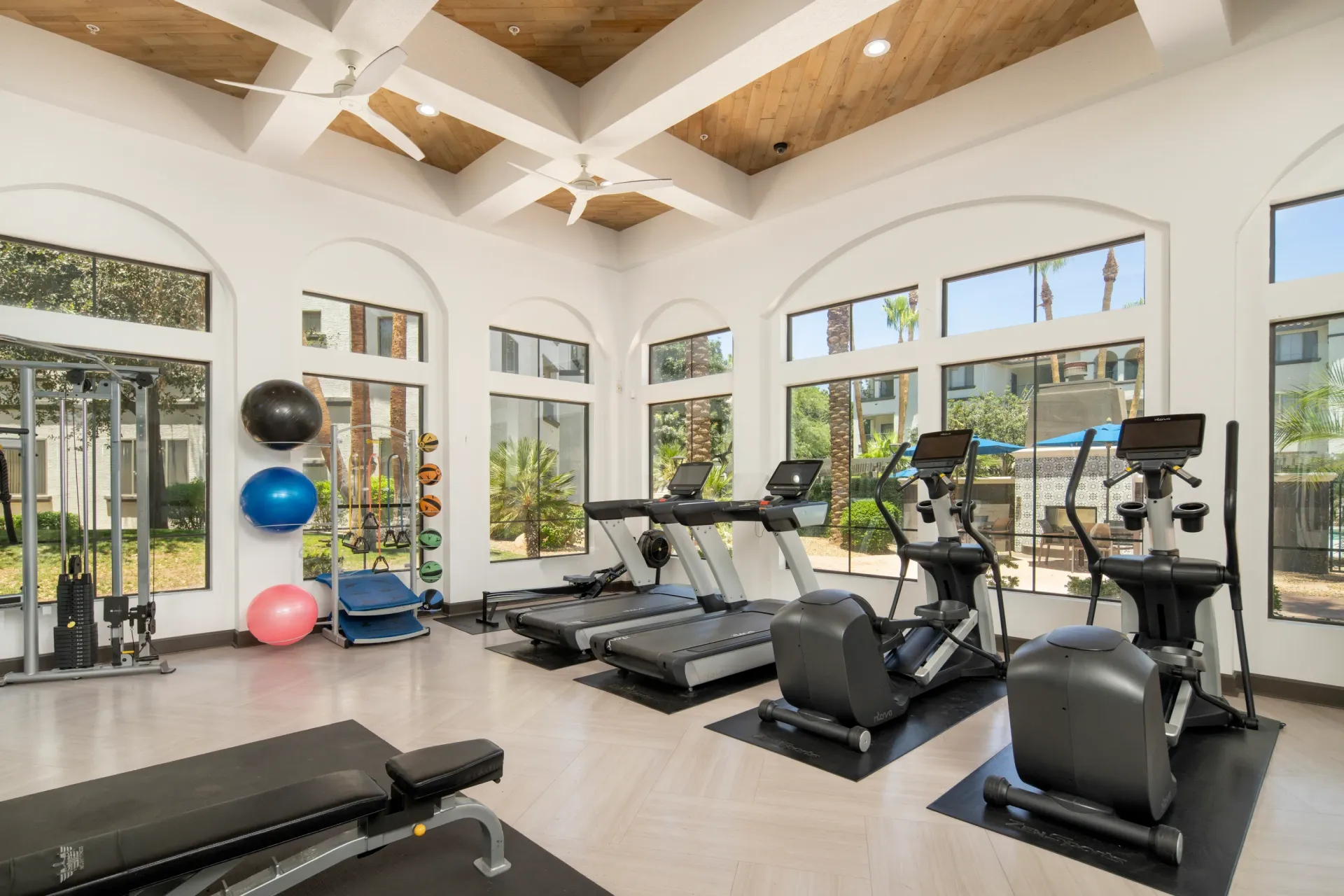 Fitness center with treadmills, elliptical machines, weight bench, and free weights.
