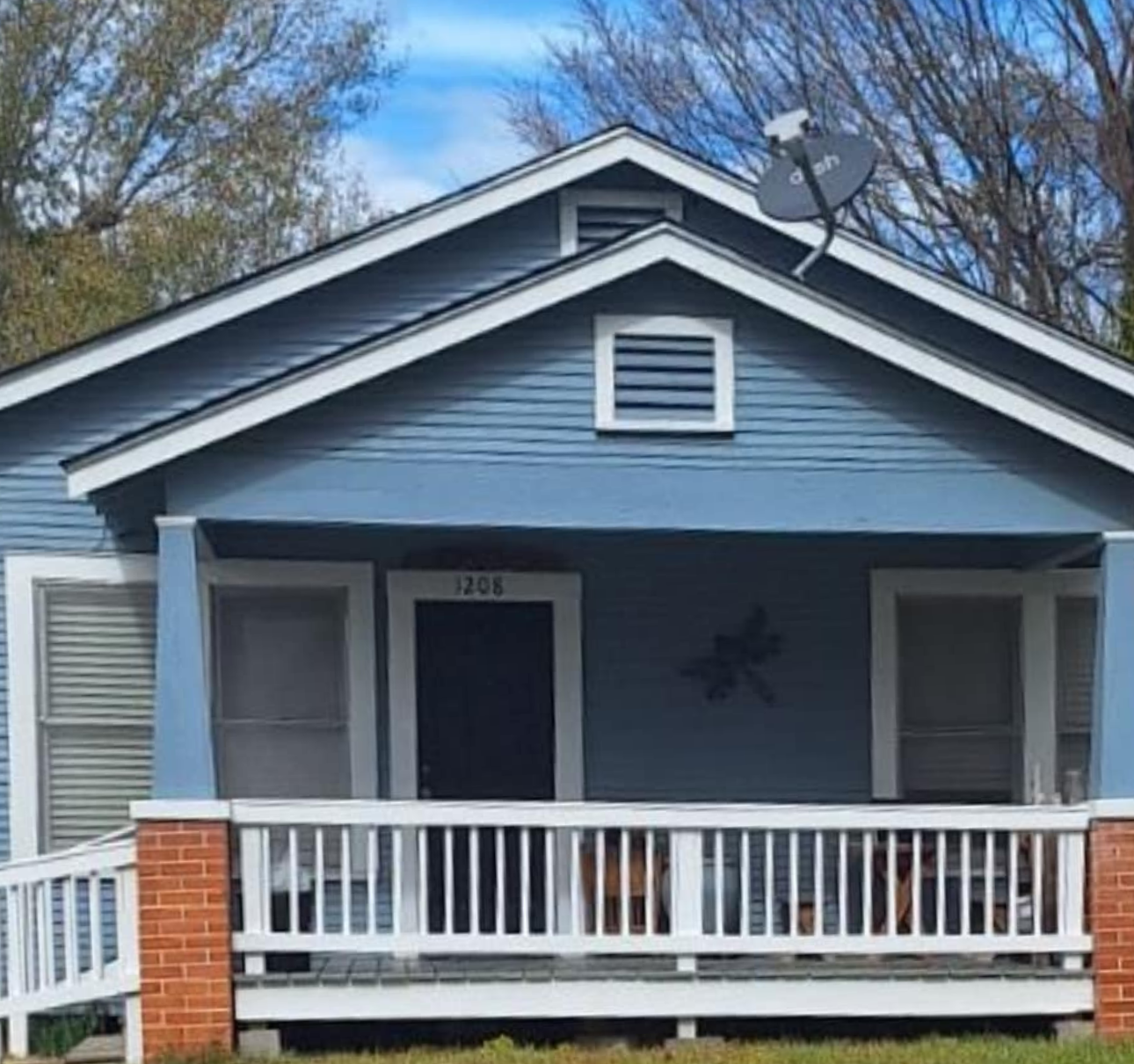 Blue bungalow house with white trim, porch, and satellite dish.