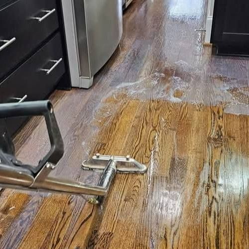 A vacuum cleaner is cleaning a wooden floor in a kitchen. A vacuum cleaner is cleaning a wooden floor in a kitchen.