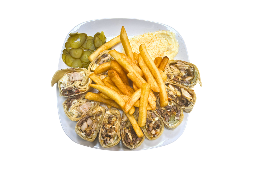 A plate of food with french fries and pickles on a white background.