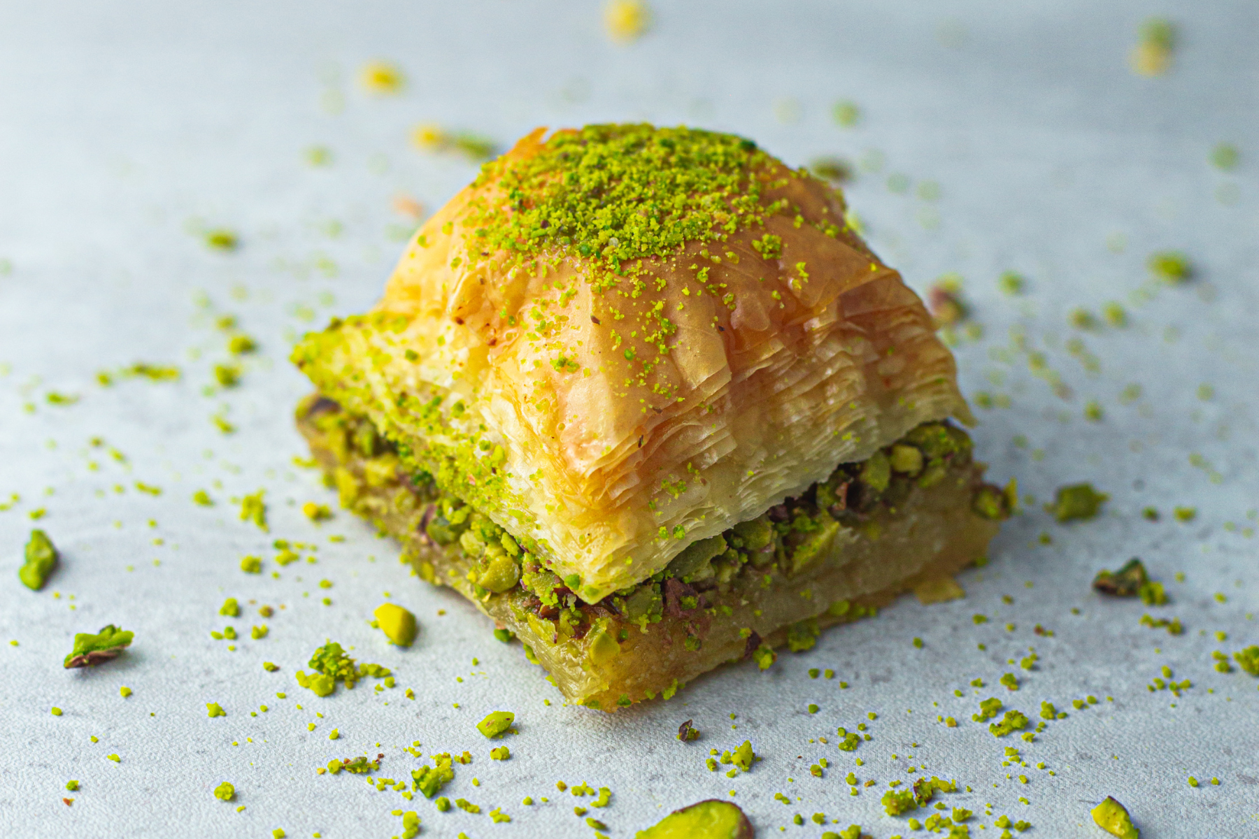 A close up of a baklava with pistachios on top on a table.