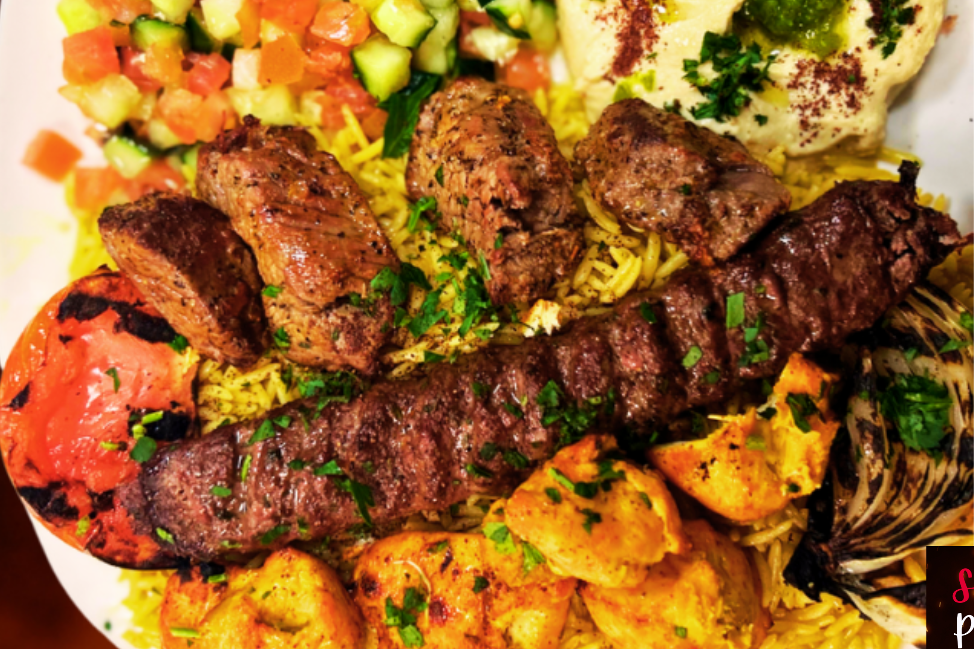 A plate of food with meat , rice , and vegetables on a table.