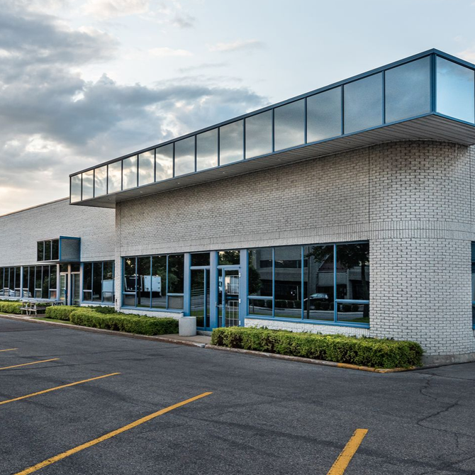 Modern commercial building with glass entrance and empty parking lot at sunset
