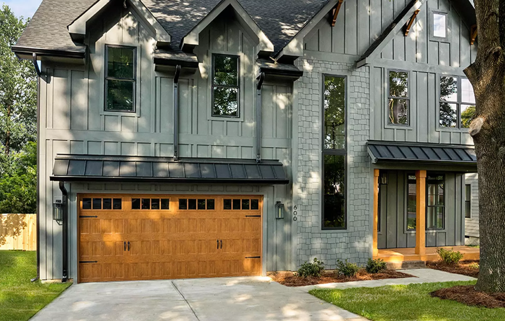 Steel two car garage door with honey oak wood finish color with a window top section and black decorative hardware in Venice