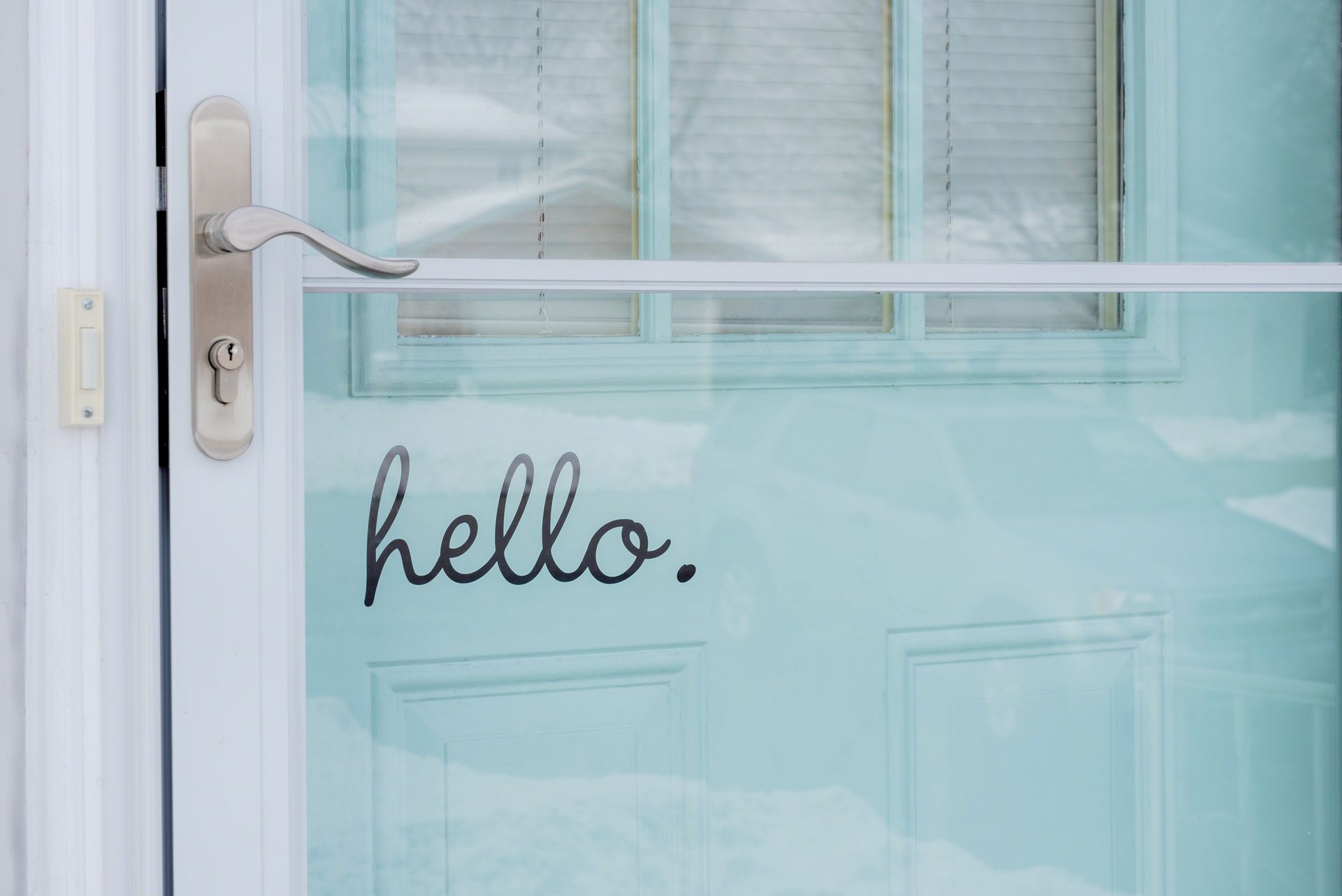 A front door with a storm door painted turquoise blue with the word hello. A front door with a storm door painted turquoise blue with the word hello.