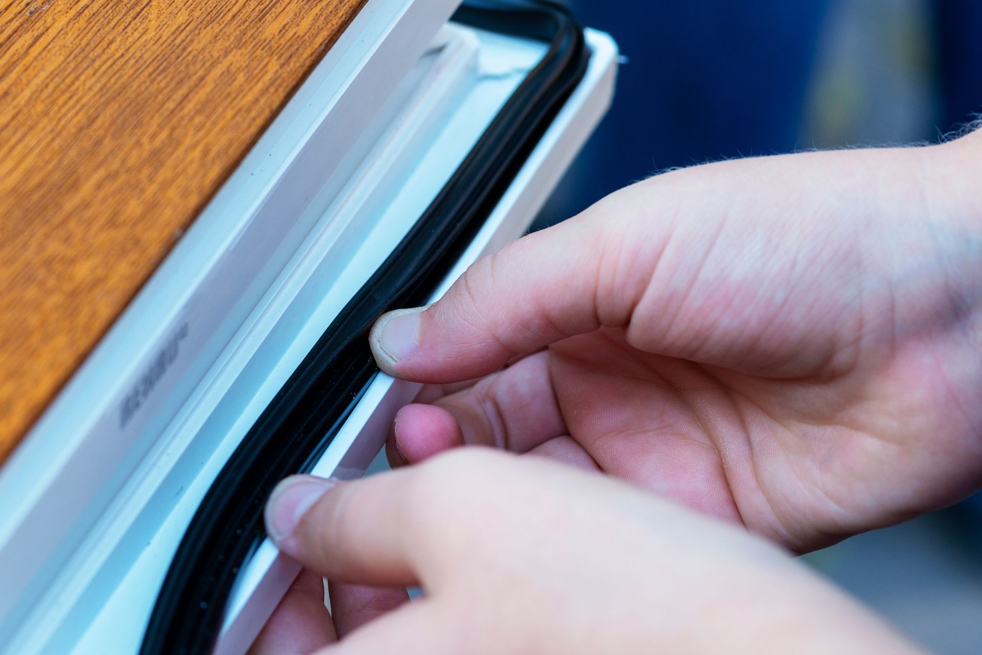 A close-up of a contractor’s hands applying strip insulation to a door. A close-up of a contractor’s hands applying strip insulation to a door.