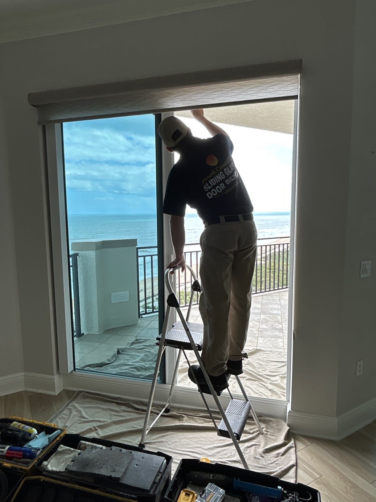 Smooth Coast technician servicing a sliding glass door in a coastal condominium.