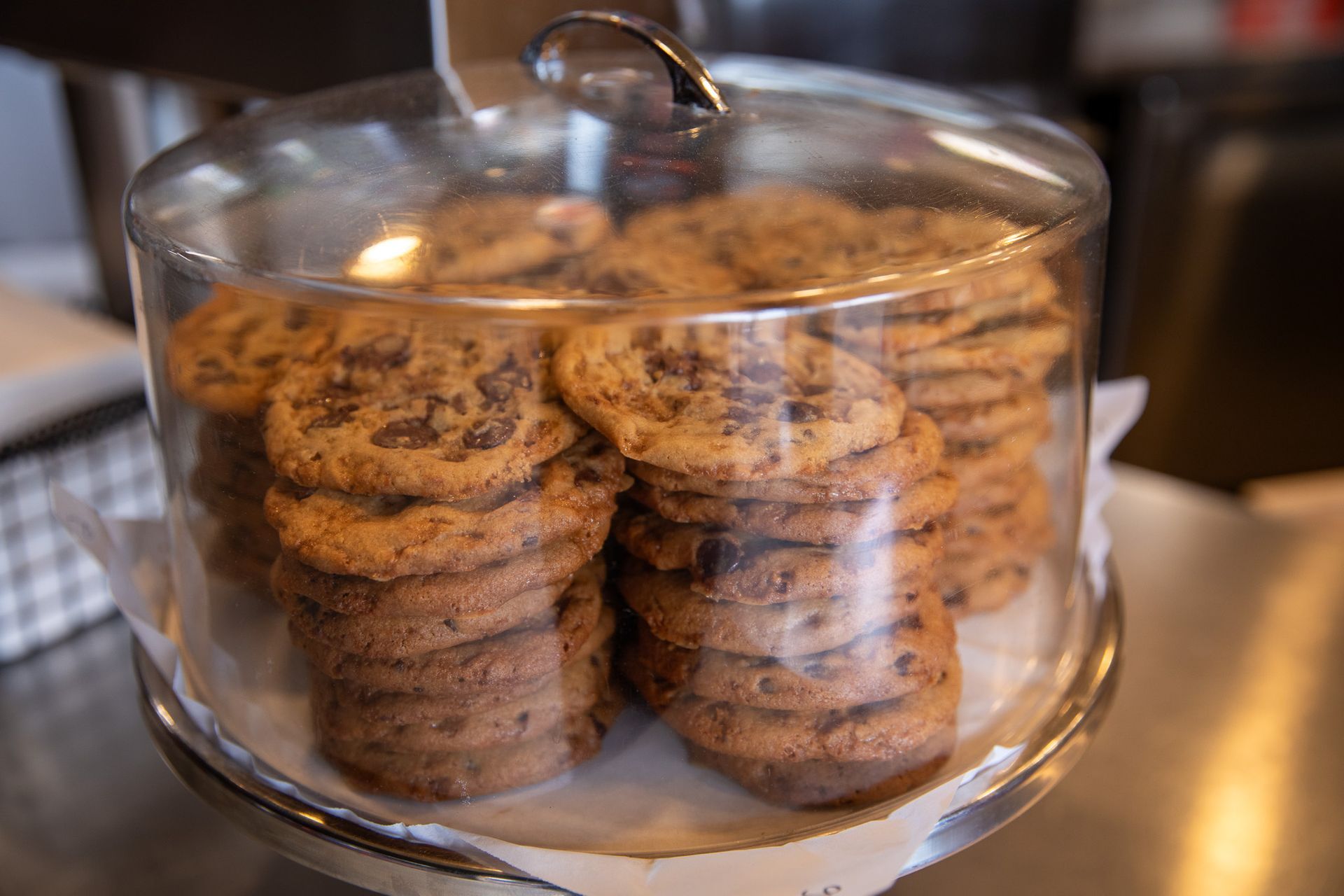 A glass dome filled with chocolate chip cookies is sitting on a table.