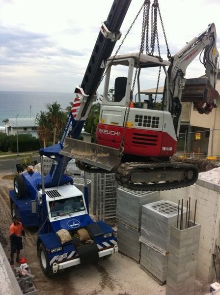 A Red and White Excavator is Being Lifted by a Crane — CA Crane Hire in Beerwah, QLD