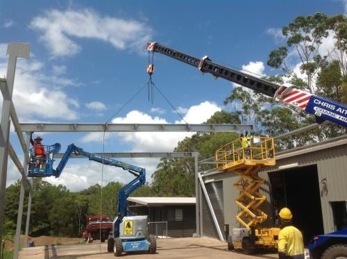 A Crane is Lifting a Metal Structure in Front of a Building — CA Crane Hire in Beerwah, QLD