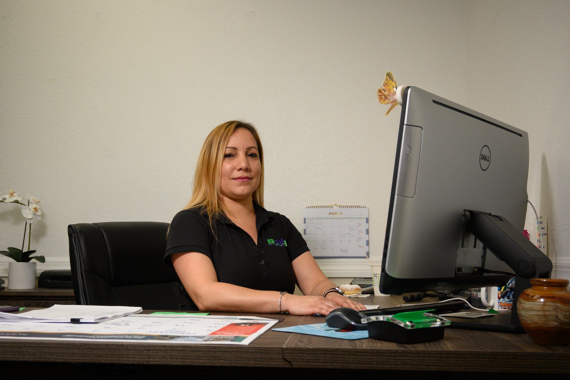 A woman is sitting at a desk in front of a computer.