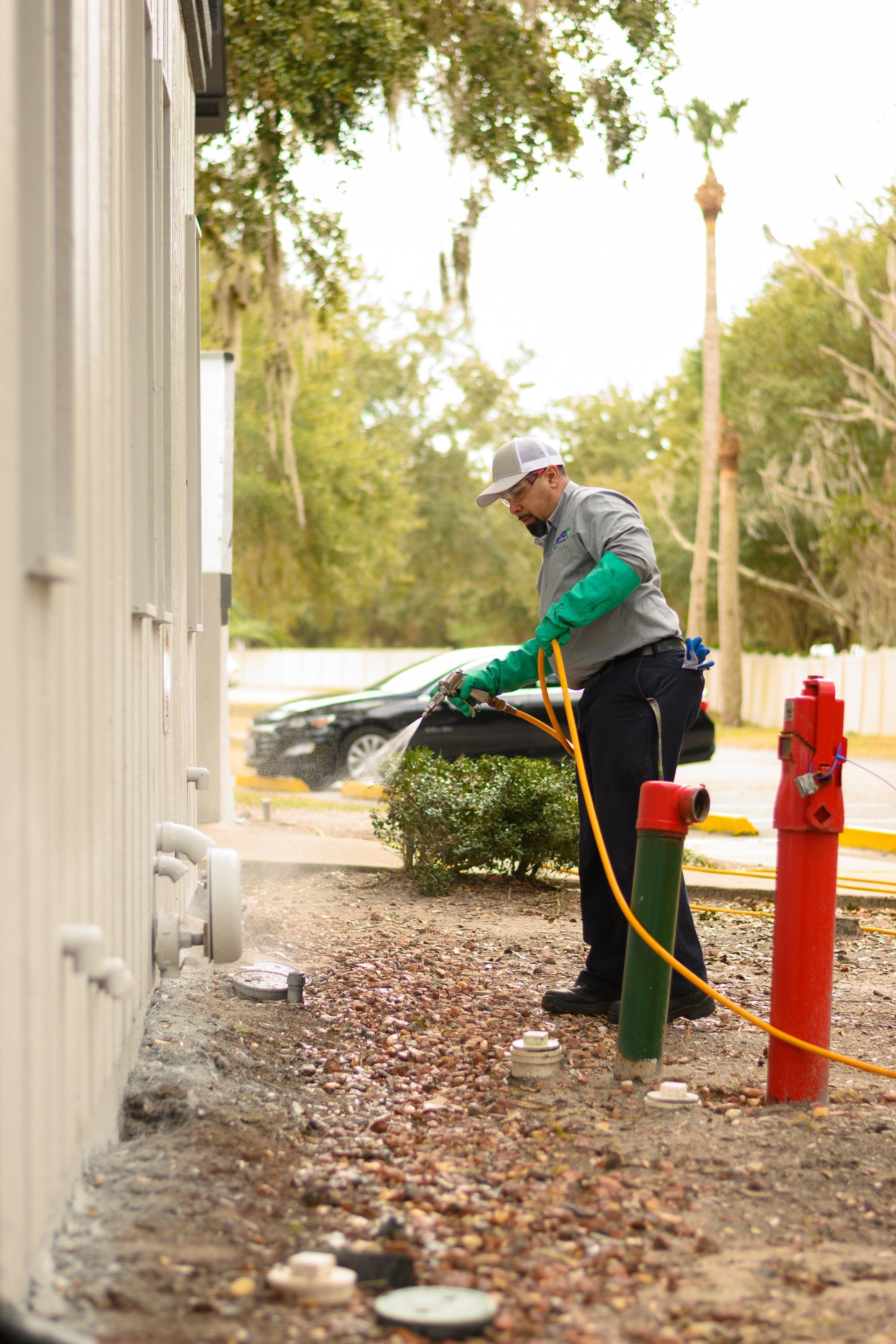 A man is spraying a fire hydrant with a hose.