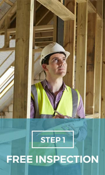 A man wearing a hard hat and safety vest is standing in a building under construction.