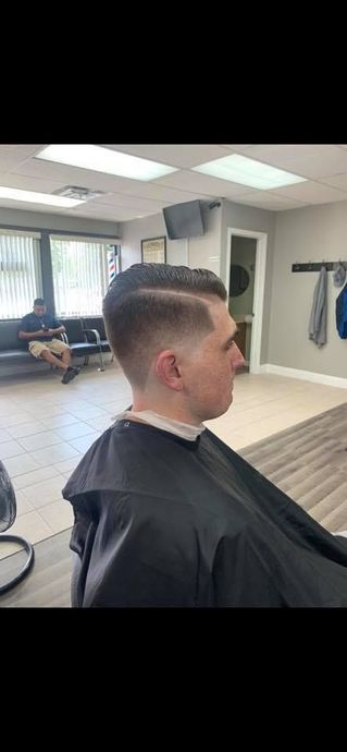 A man is getting his hair cut at a barber shop.