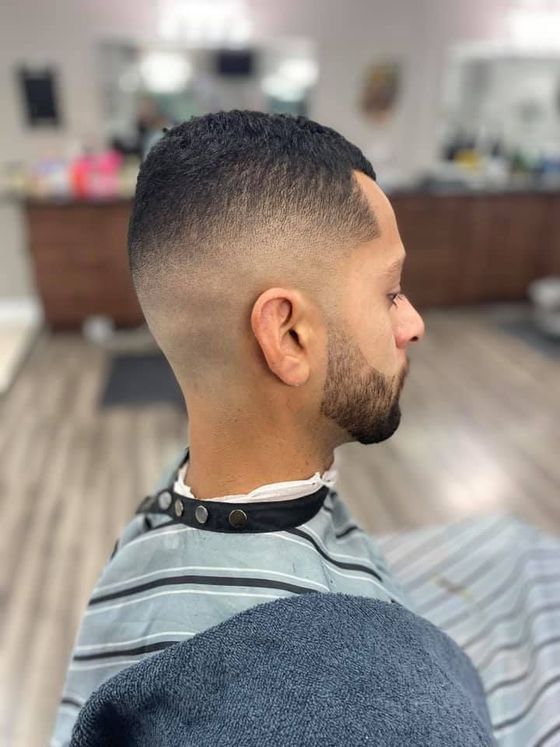 A man with a beard is getting his hair cut at a barber shop.