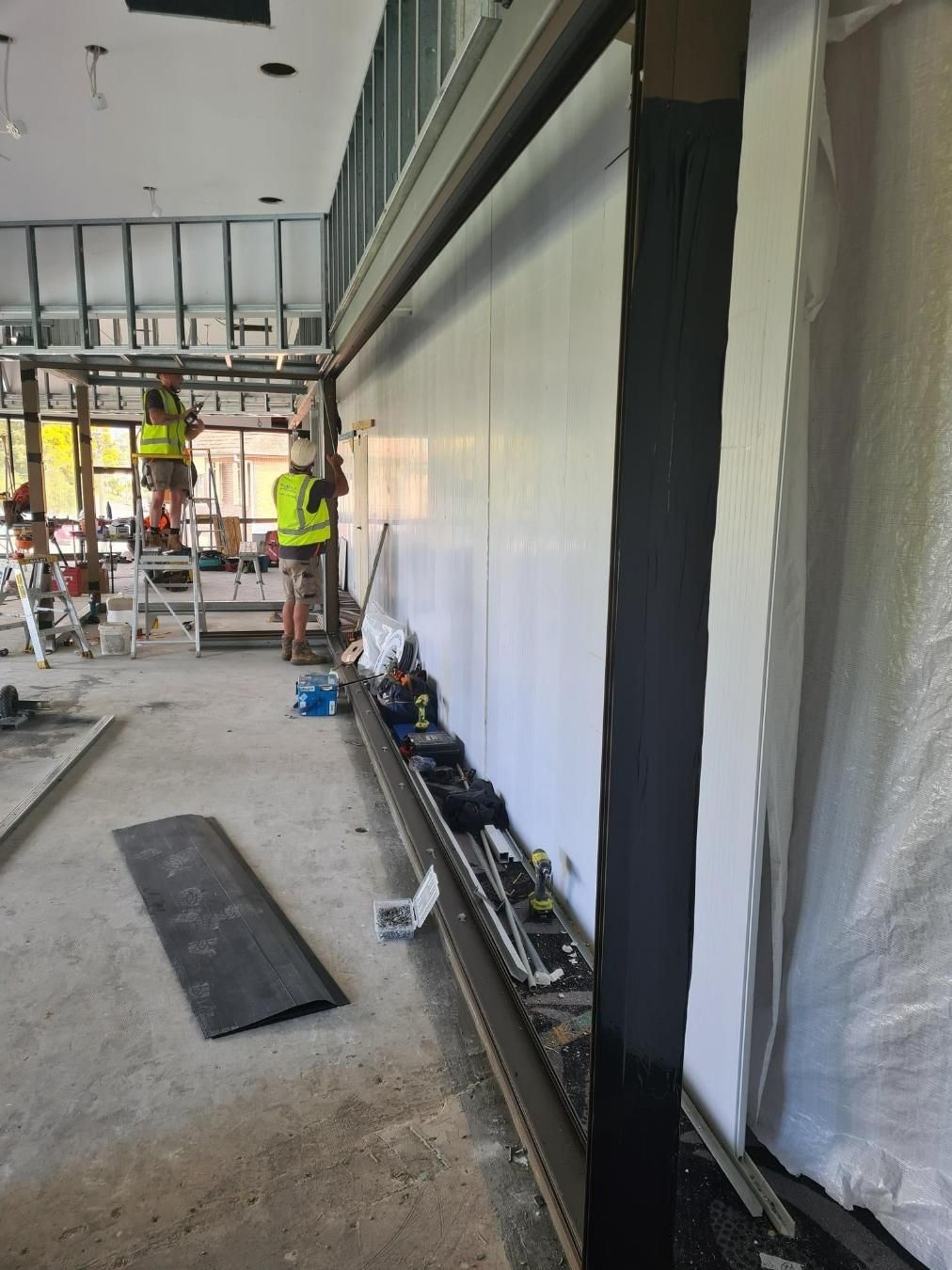 A Group Of Construction Workers Are Working On A Wall — Datco Windows & Doors Pty Ltd In South Murwillumbah, NSW