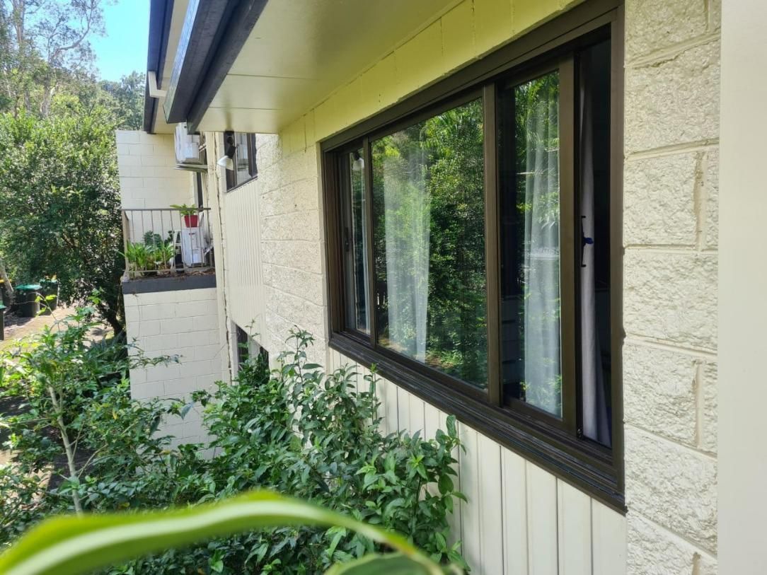 Window With Brown Frame and Glass Reflecting Greenery — Datco Windows & Doors Pty Ltd In Toowoomba, QLD