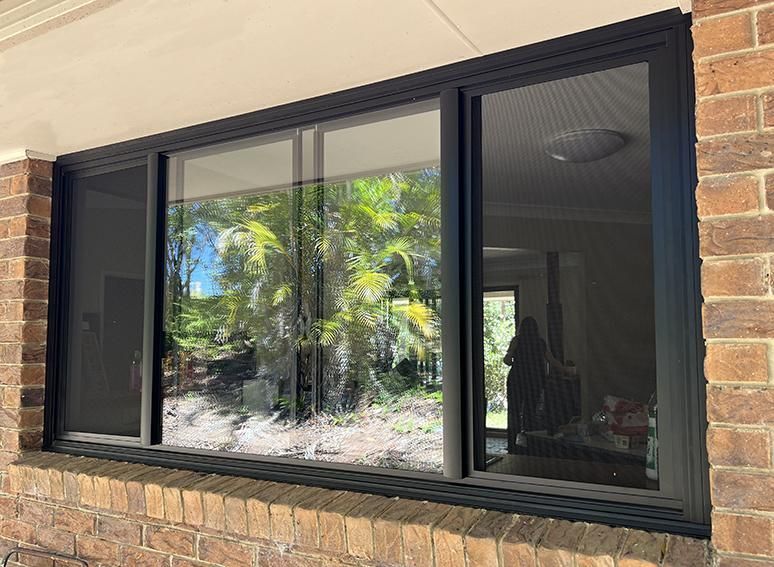 A Large Window With A Screen On It Is On A Brick Wall — Datco Windows & Doors Pty Ltd In Byron Bay, NSW