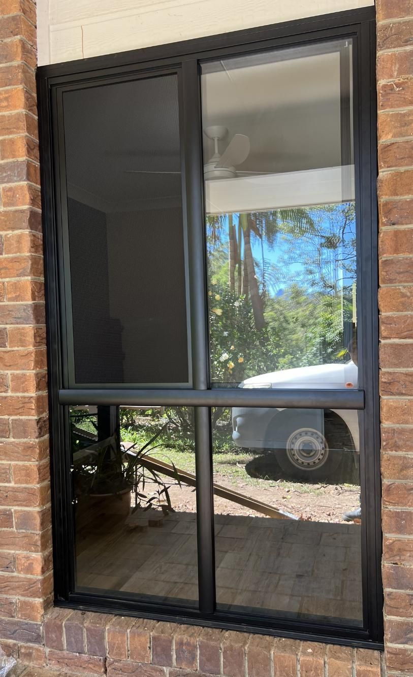 A Window With A Black Frame Is On A Brick Wall — Datco Windows & Doors Pty Ltd In Ballina, NSW