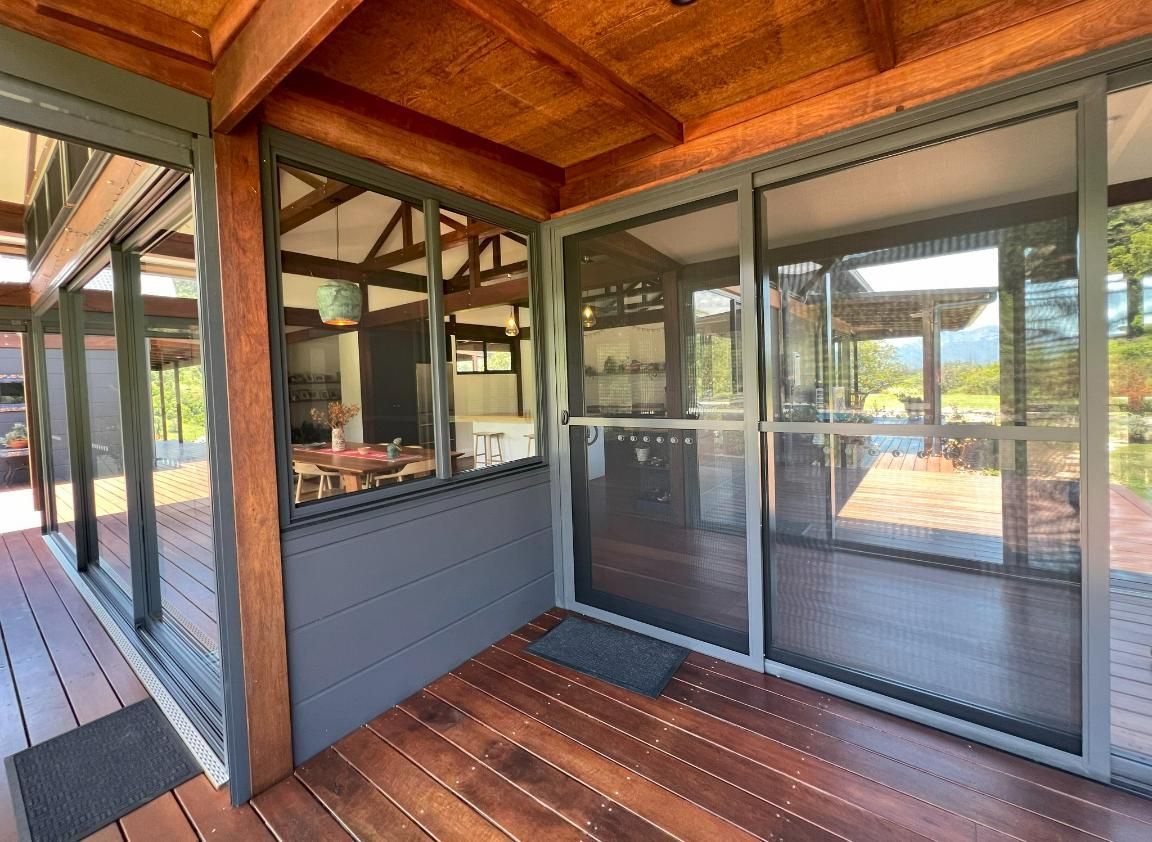 A Screened In Porch With Sliding Glass Doors And A Wooden Deck — Datco Windows & Doors Pty Ltd In Casino, NSW