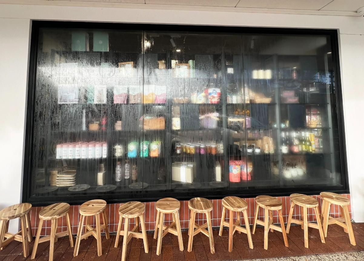 A Row Of Wooden Stools Are Lined Up In Front Of A Glass Wall — Datco Windows & Doors Pty Ltd In Grafton, NSW