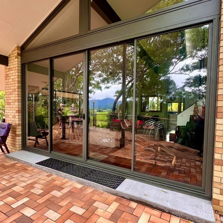 A House With A Lot Of Windows And A Brick Patio — Datco Windows & Doors Pty Ltd In South Murwillumbah, NSW