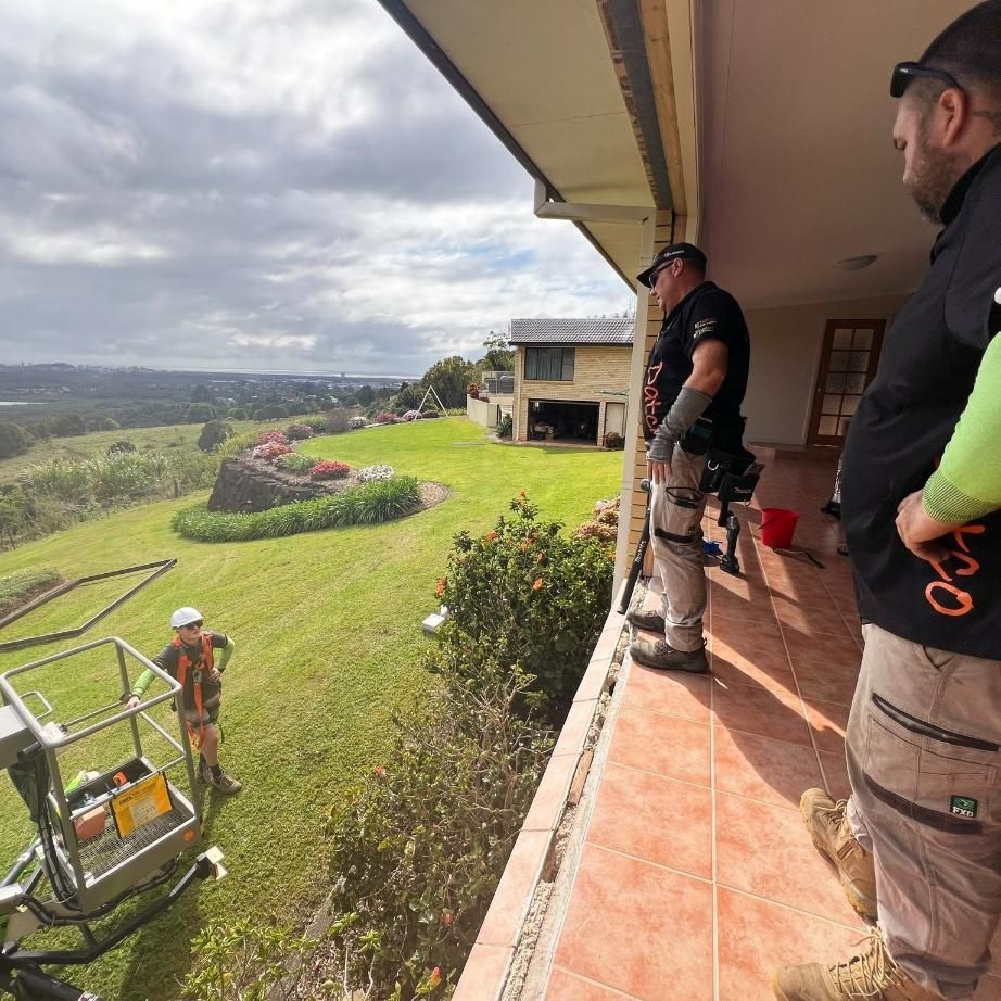 Two Men Are Standing On A Balcony Looking Out Over A Lush Green Field — Datco Windows & Doors Pty Ltd In South Murwillumbah, NSW