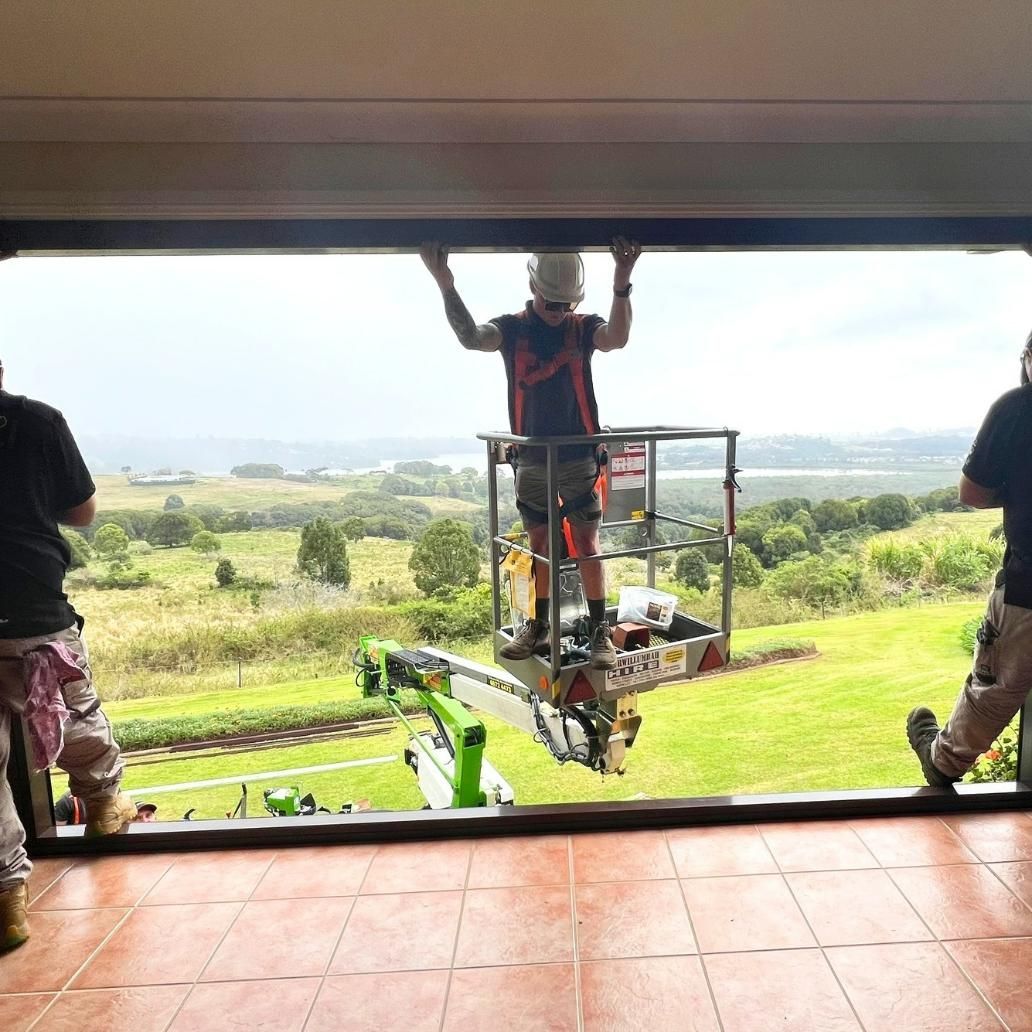 A Man Is Standing On A Lift Looking Out Of A Window — Datco Windows & Doors Pty Ltd In South Murwillumbah, NSW