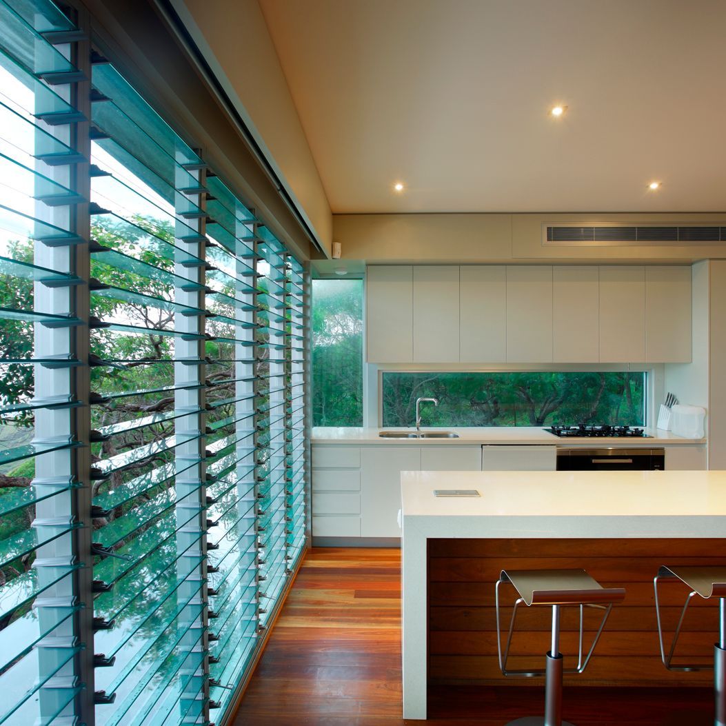 Modern Kitchen With Glass Louvre Windows, White Countertops, and Wooden Floors — Datco Windows & Doors Pty Ltd In South Murwillumbah, NSW
