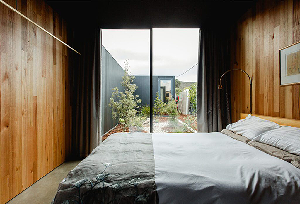 Modern bedroom with wood-paneled walls and large glass doors — Datco Windows & Doors Pty Ltd In South Murwillumbah, NSW
