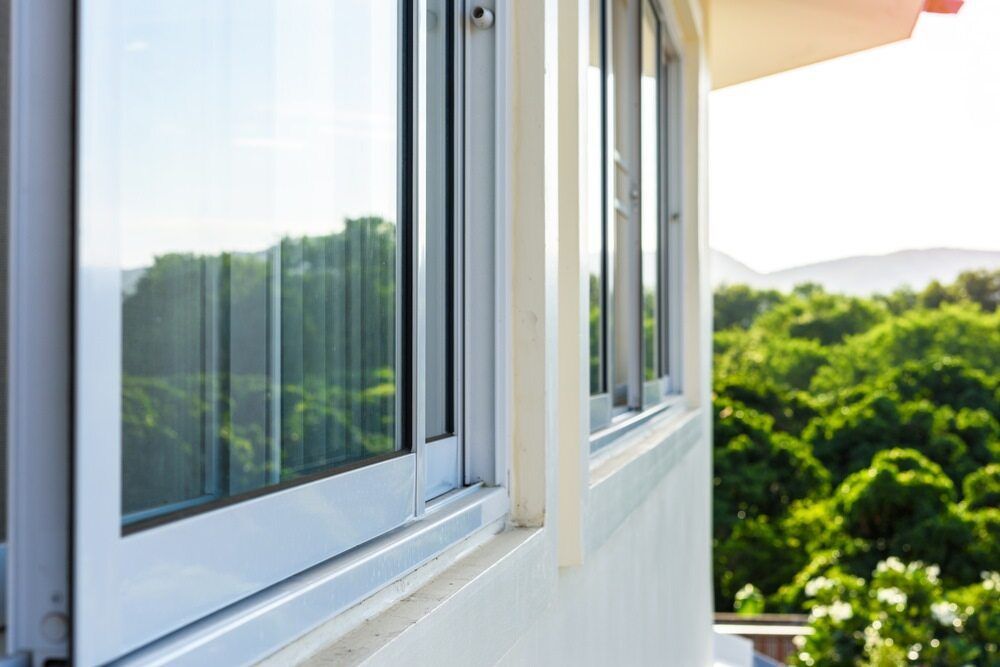 Silver-framed Windows on a White Building, Reflecting Trees and a Bright Sky — Datco Windows & Doors Pty Ltd In South Murwillumbah, NSW