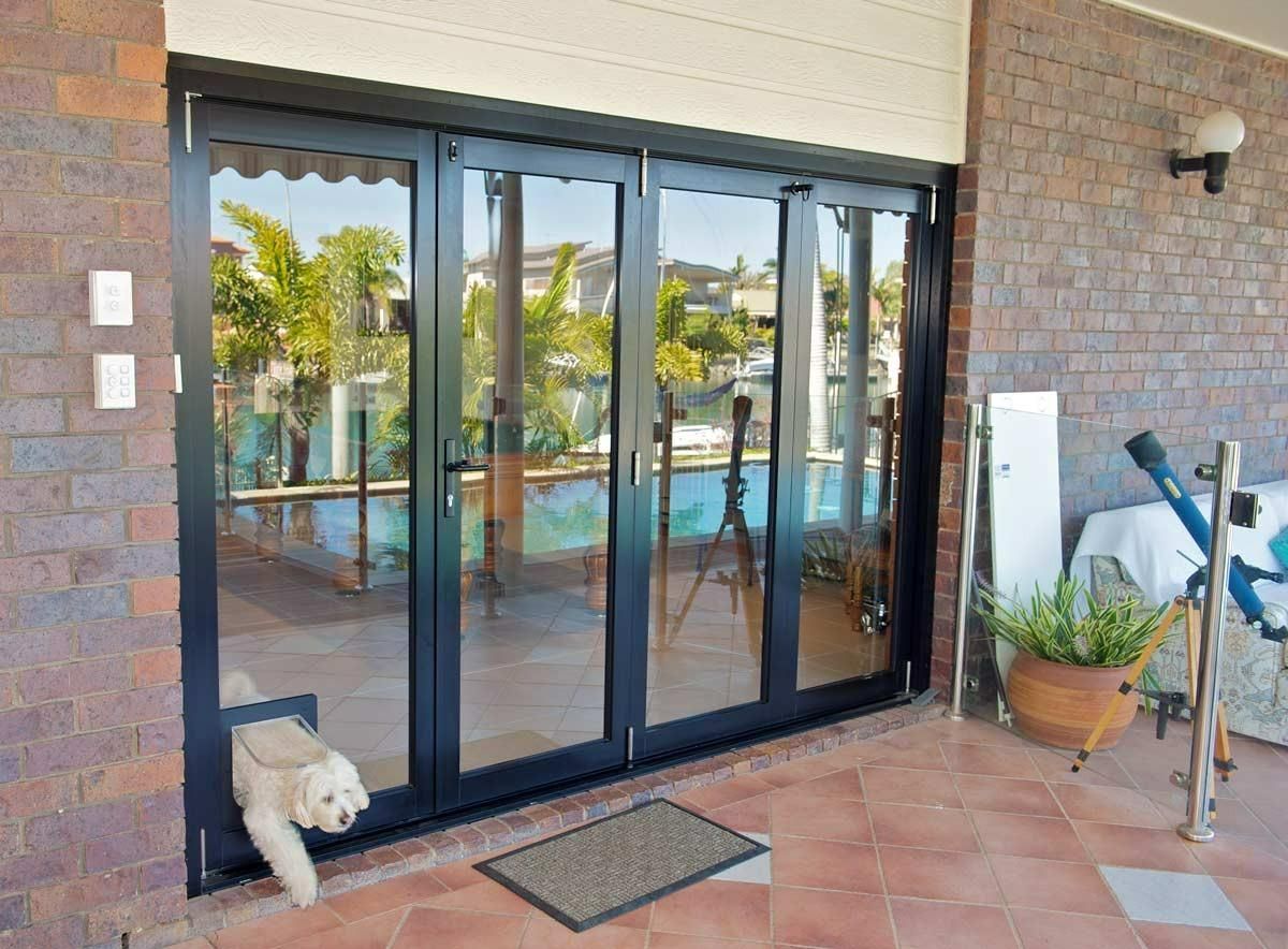 A Dog is Looking Out of a Sliding Glass Door — Datco Windows & Doors Pty Ltd In South Murwillumbah, NSW