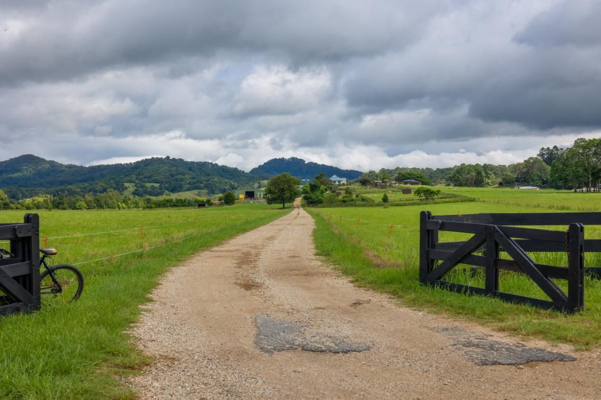 A Dirt Road Going Through A Grassy Field With Mountains In The Background — Datco Windows & Doors Pty Ltd In Kyogle, NSW