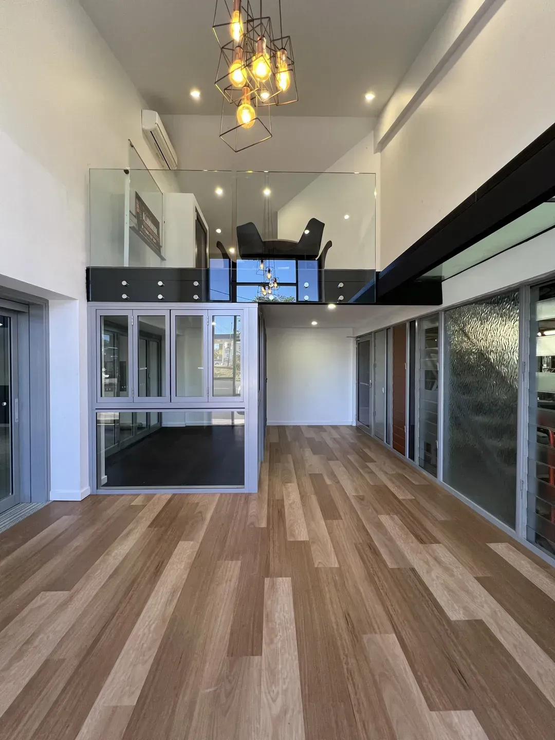 Interior Showroom With Wood Floors, Display Windows, and a Glass-walled Mezzanine — Datco Windows & Doors Pty Ltd In Coffs Harbour, NSW