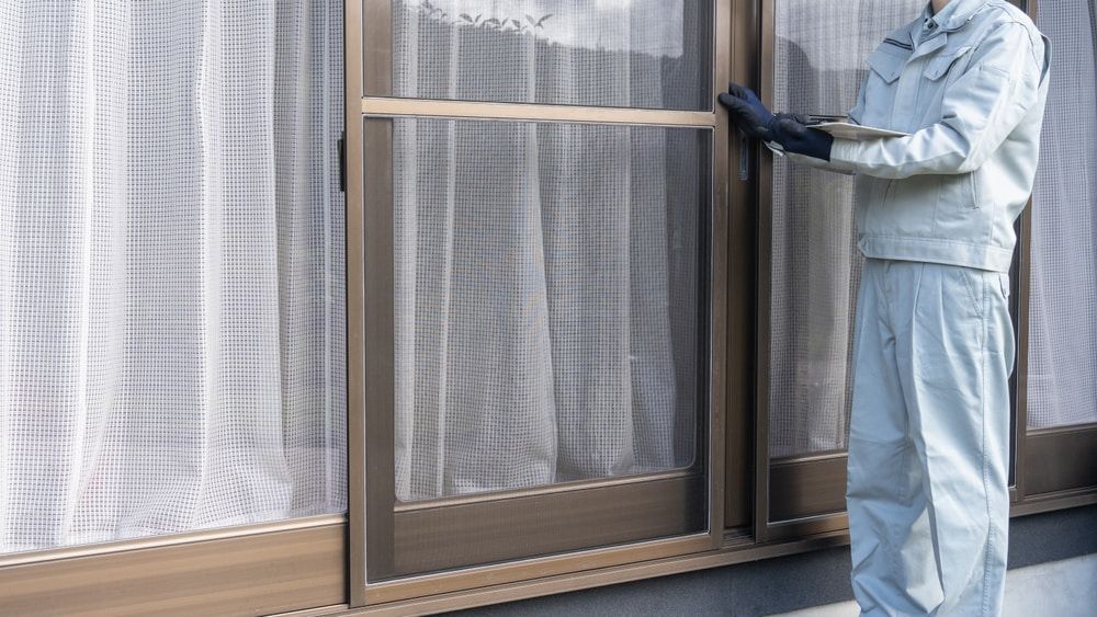 A Man Is Standing In Front Of A Window With A Screen On It — Datco Windows & Doors Pty Ltd In South Murwillumbah, NSW