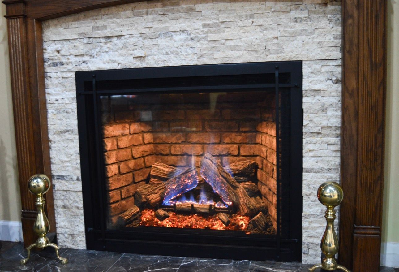 Brick fireplace with a black frame and glowing fire, flanked by wooden trim and brass andirons.