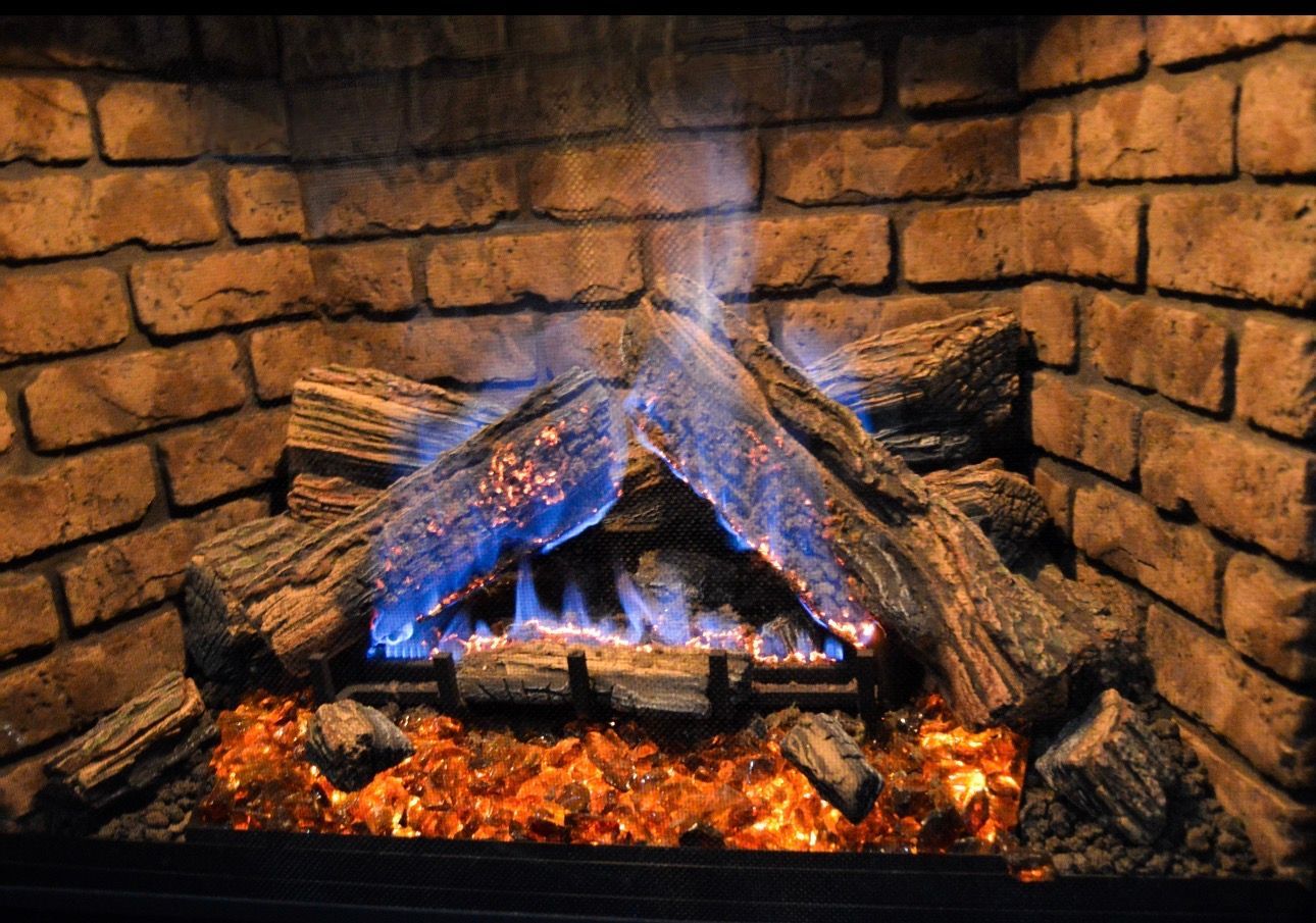 Lit fireplace with glowing logs and blue flames against a brick hearth