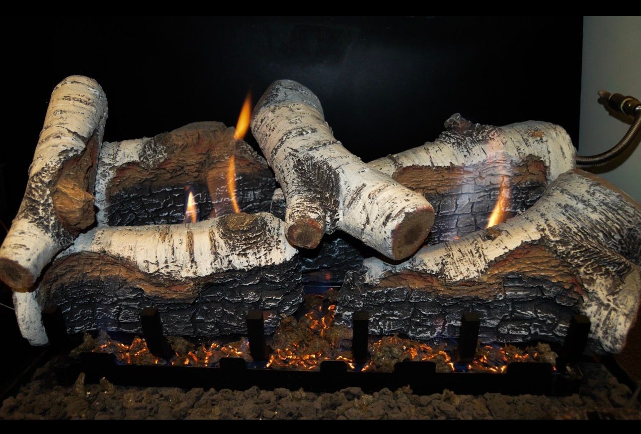 Burning logs in a fireplace with glowing embers and small flames