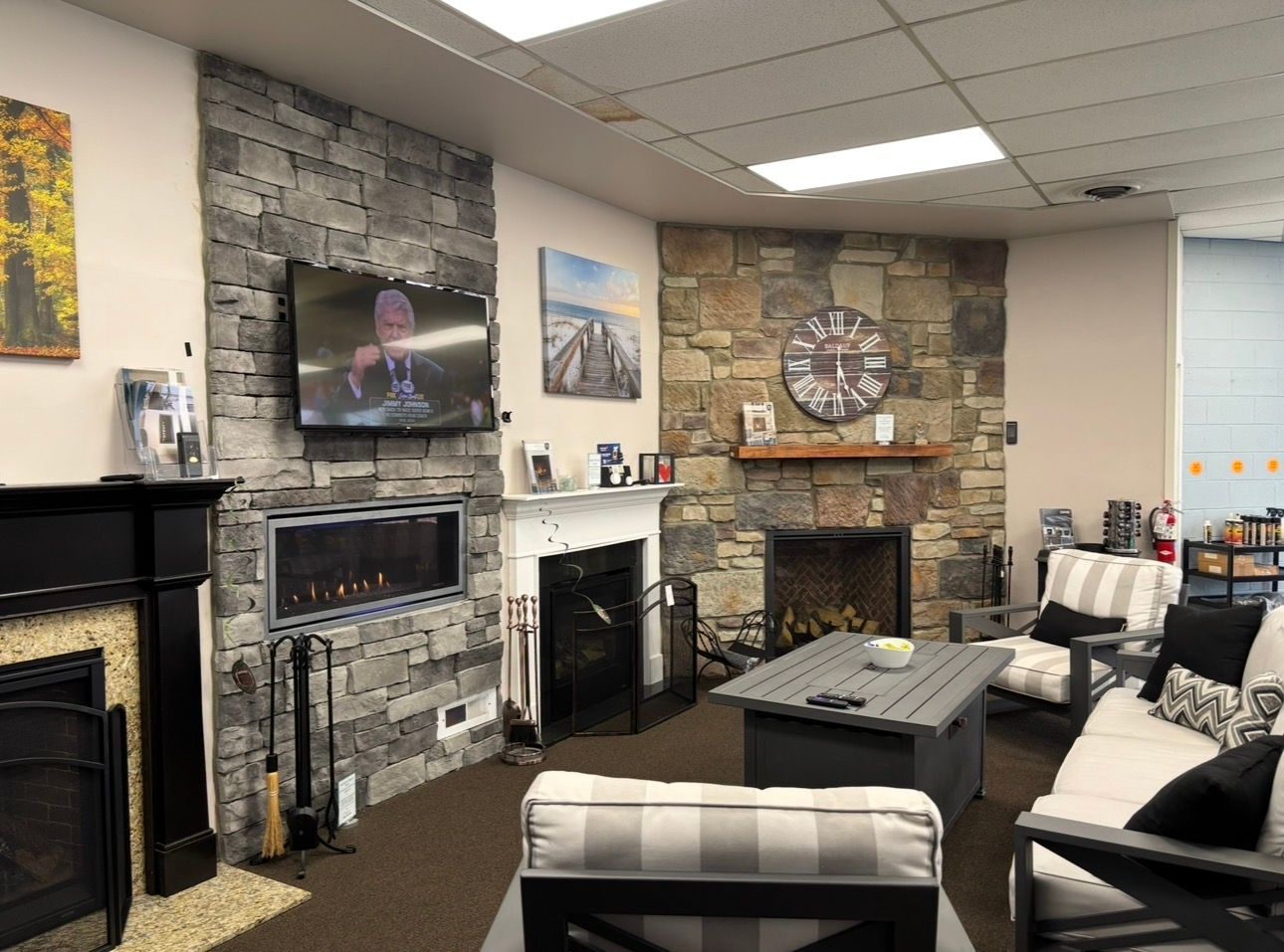 Cozy living room with stone fireplace, wall-mounted TV, and black-and-white chairs סביב a coffee table