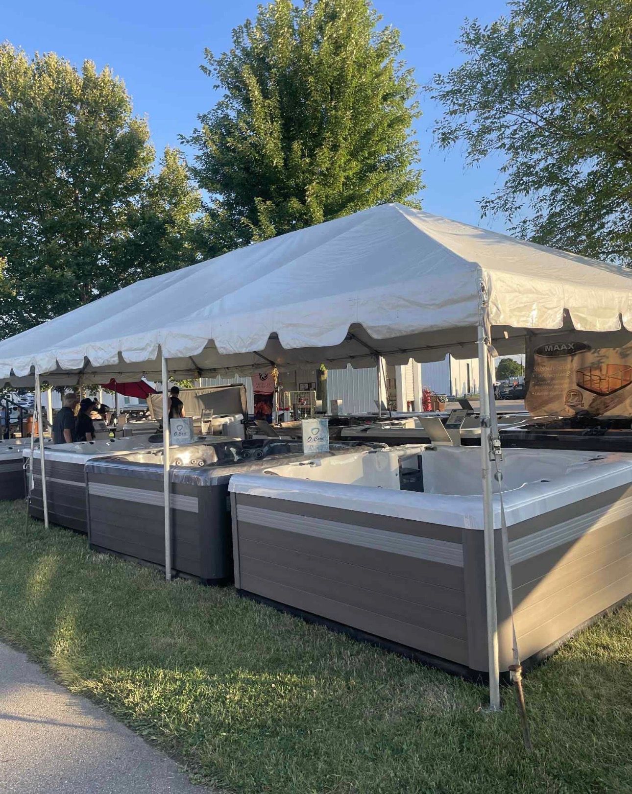 Outdoor buffet under a white tent at a park, with tables and chairs on a grassy lawn.