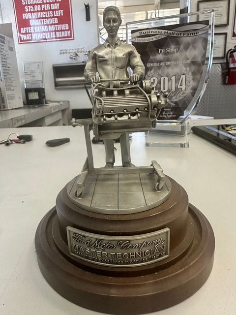 Gold trophy statue on a wooden base displayed on a counter in a shop or office