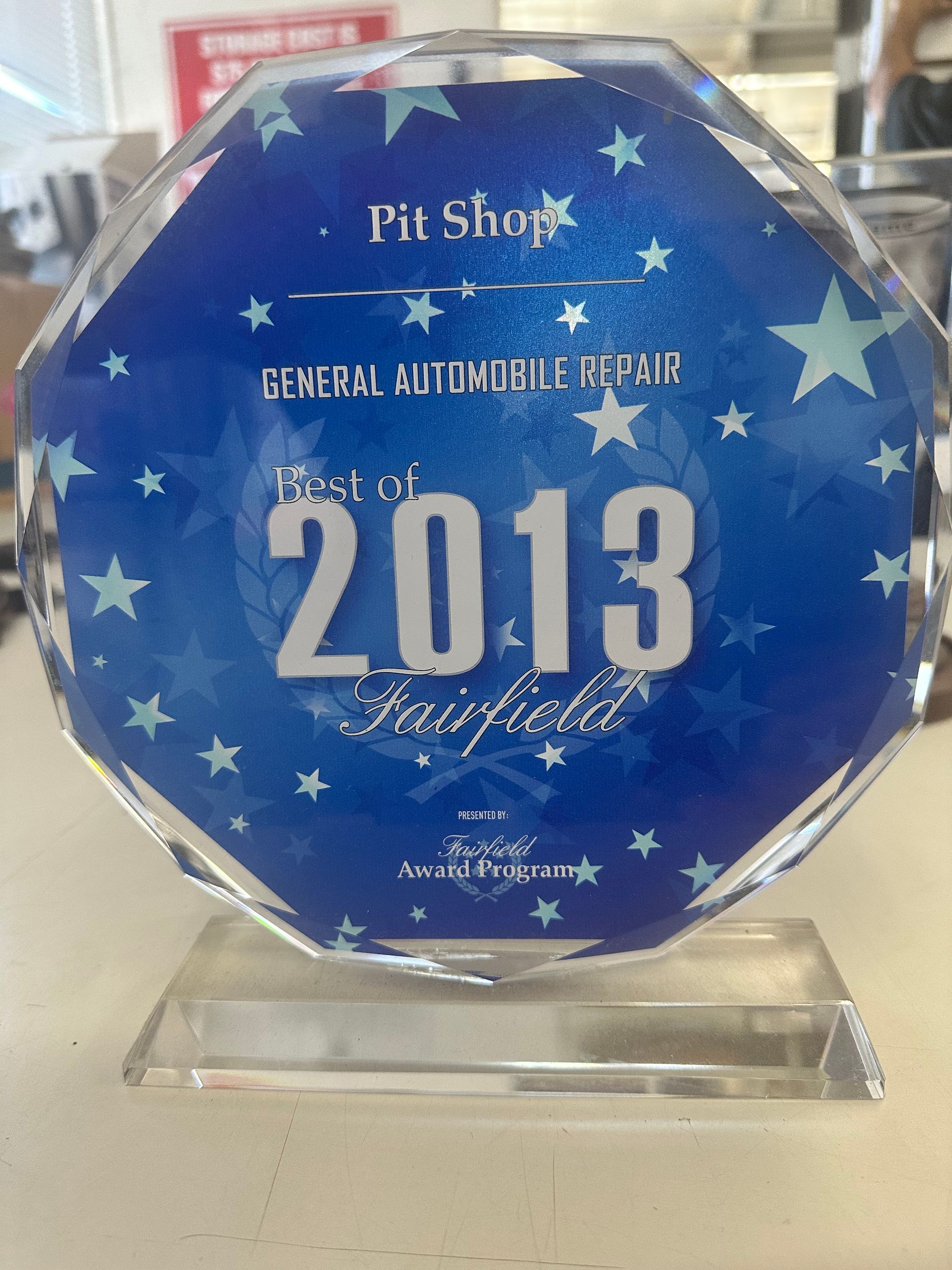 Blue glass award plaque with stars, reading Pin Shop General Automobile Repair Top 2013.