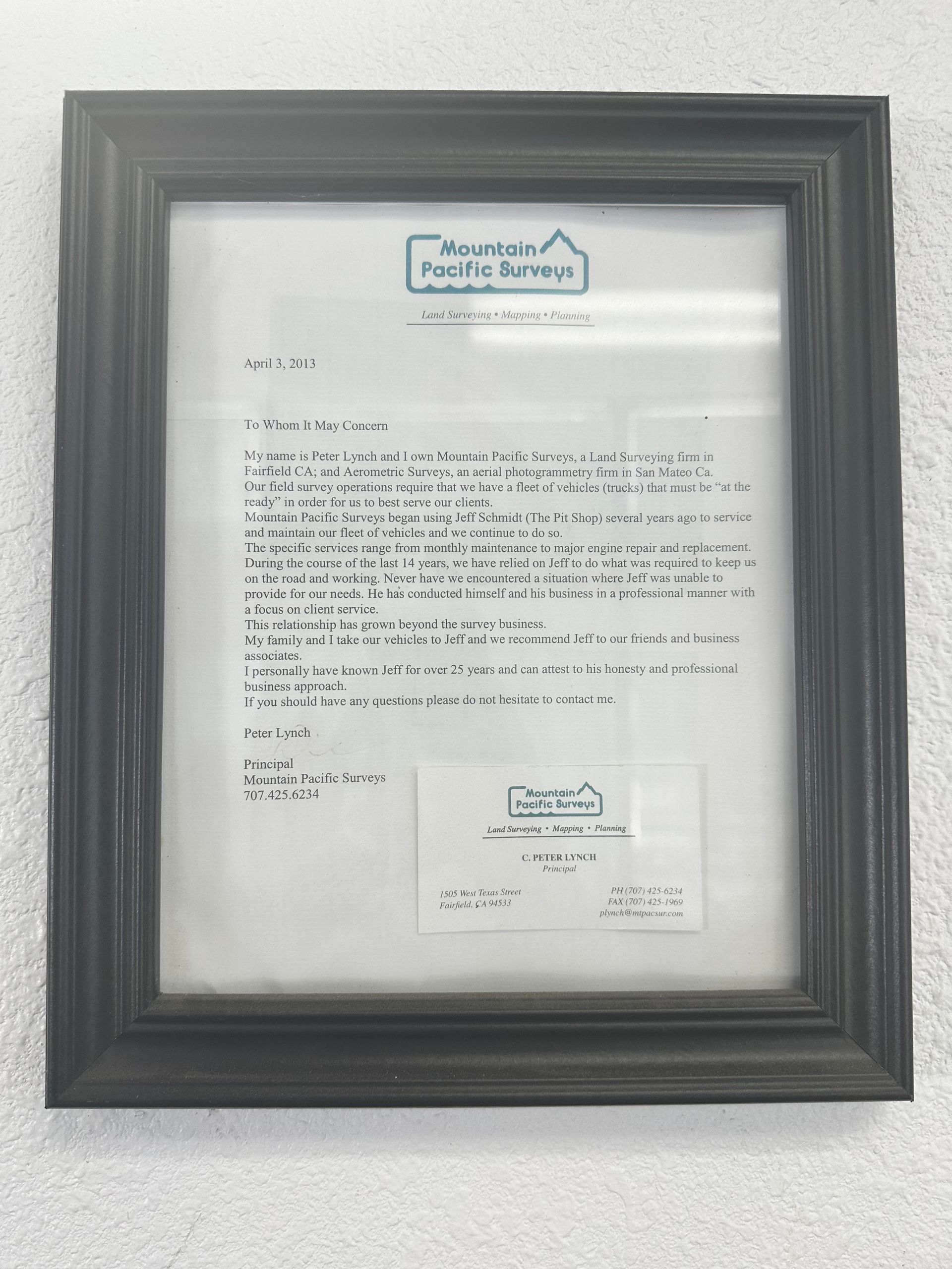 Framed certificate or letter with a small logo, displayed on a light wall.