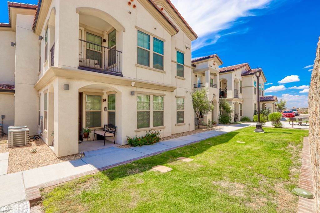 A large white apartment building with a large lawn in front of it.