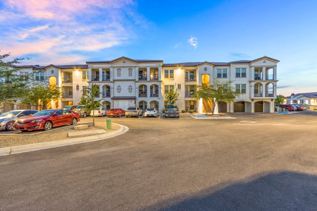 A large apartment building with a lot of cars parked in front of it.