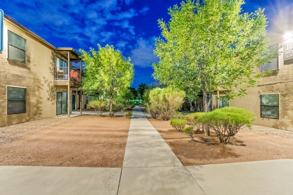 A walkway leading to a building with trees in front of it.