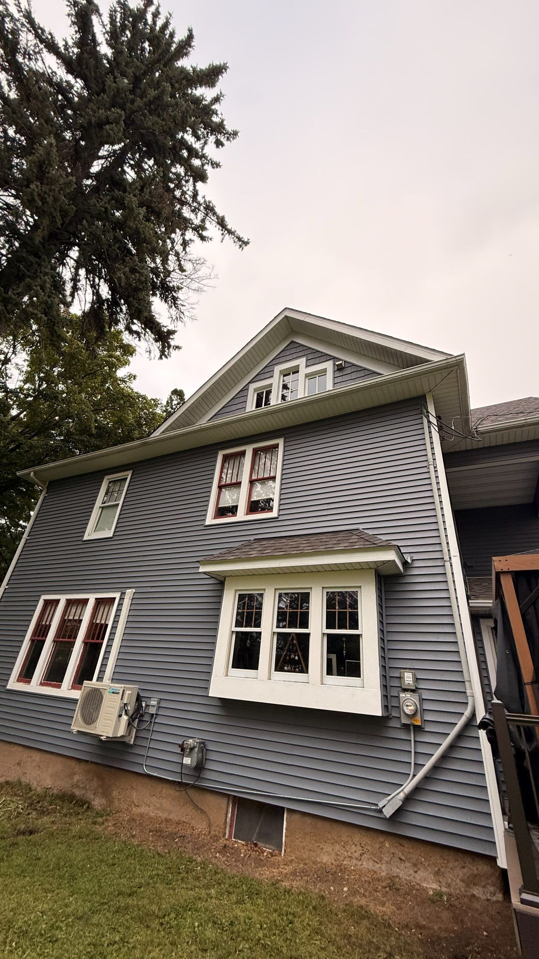 A two-story blue house exterior with a distinct, swirling optical illusion pattern on the siding, under a gray sky.